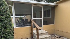 A screened porch with a wooden staircase leading to a covered area.