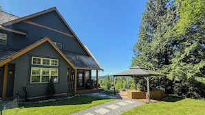 A two-story house with a covered porch and a stone pathway leading to a gazebo.