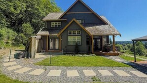 A two-story house with a gabled roof, a front porch, and a covered patio area.