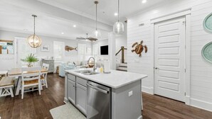 Una cucina moderna con isola centrale, elettrodomestici in acciaio inossidabile e illuminazione a sospensione.