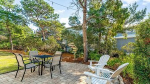 An outdoor patio area with a table and chairs, surrounded by trees and plants. - 🦩Book Me Baby! ~ Take It Easy On 30A🦩 (Santa Rosa Beach)