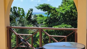 A balcony with a view of the ocean and lush greenery. - Rosita with a Waterfall Jacuzzi & Rain Forest feel (Lambeau)