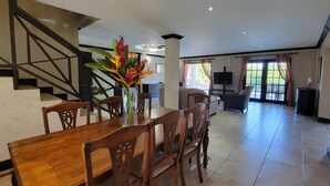 A spacious living area with a dining table, chairs, and a staircase. - Rosita with a Waterfall Jacuzzi & Rain Forest feel (Lambeau)