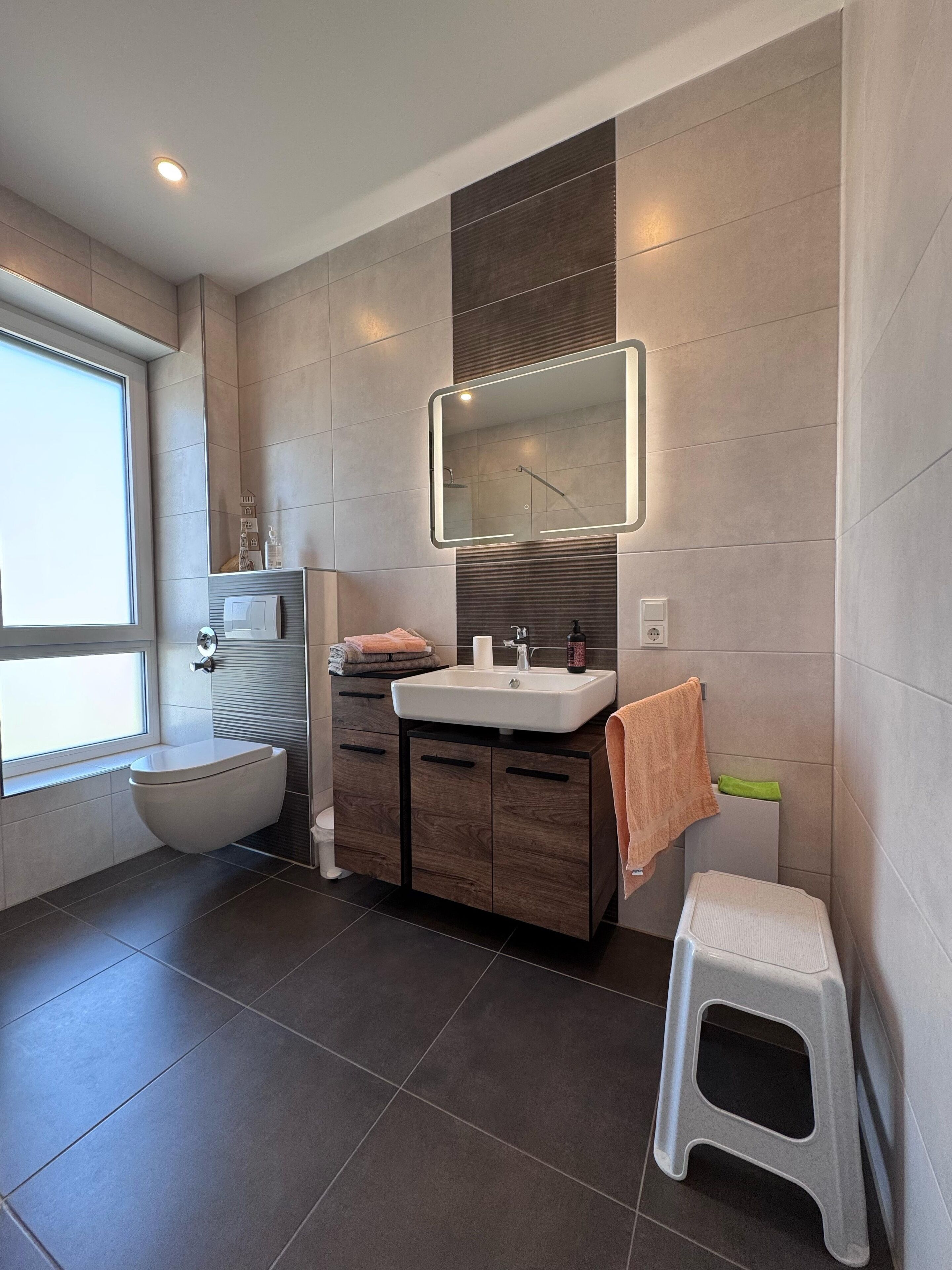 A modern bathroom with a toilet, sink, and mirror.
