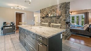 Una cocina moderna con una isla grande, pared de acento de piedra y electrodomésticos integrados.