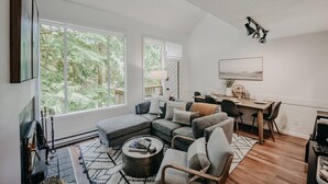 Ein modernes Wohnzimmer mit einem Ecksofa, einem Couchtisch und einem Essbereich mit Tisch und Stühlen.