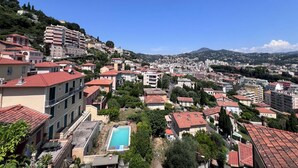 A residential area with a swimming pool, terraced houses, and a hillside with buildings. - Ground floor of a house, in a quiet location in the hills above Nice, a 1/4 h from downtown. (Nice)