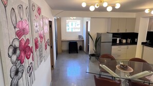 A modern kitchen with white cabinets, a glass dining table, and a large window. - Ground floor of a house, in a quiet location in the hills above Nice, a 1/4 h from downtown. (Nice)
