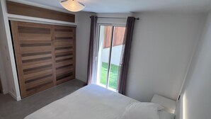 A bedroom with a large bed, a wardrobe, and a sliding door to a balcony. - Ground floor of a house, in a quiet location in the hills above Nice, a 1/4 h from downtown. (Nice)
