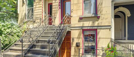 A multi-story building with a set of metal stairs leading to a wooden door.