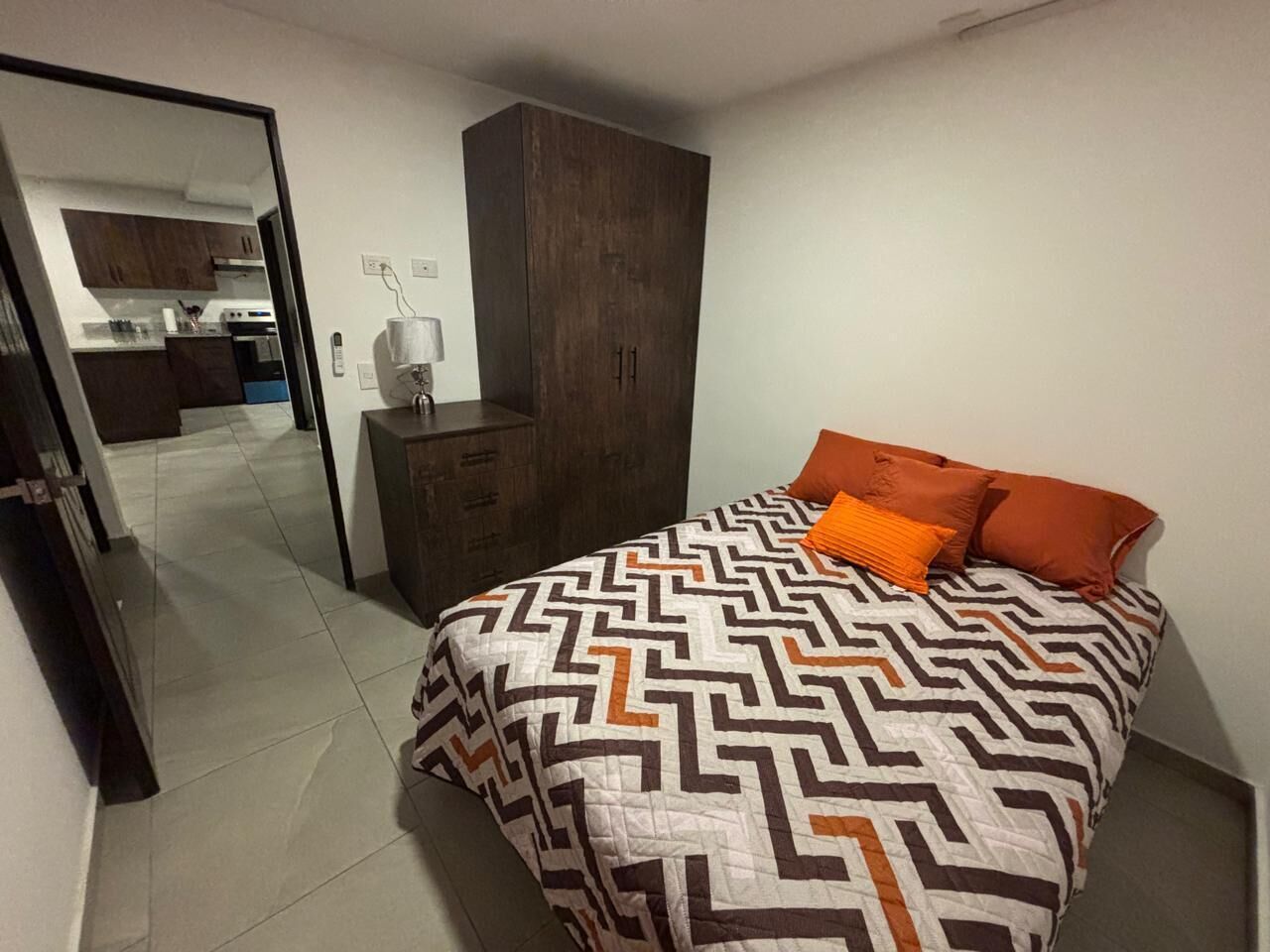 Un dormitorio con cama, armario y espejo.