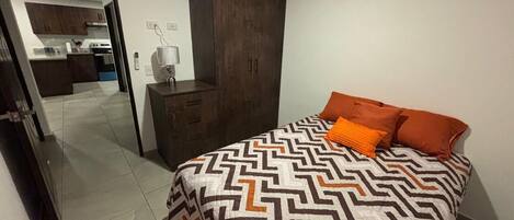 Un dormitorio con cama, armario y espejo.