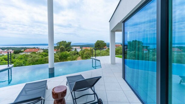 Un área de piscina moderna al aire libre, con una vista despejada del paisaje circundante y edificios distantes.