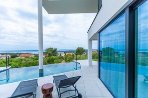 Un espace piscine extérieur moderne offrant une vue dégagée sur le paysage environnant et les bâtiments situés au loin.