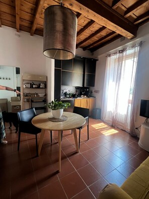 A modern kitchen with black cabinets, a wooden ceiling, and a round dining table with chairs. - Galileo Apartment (Firenze)