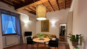 A cozy dining area with a round wooden table, black chairs, and a hanging light fixture. - Galileo Apartment (Firenze)