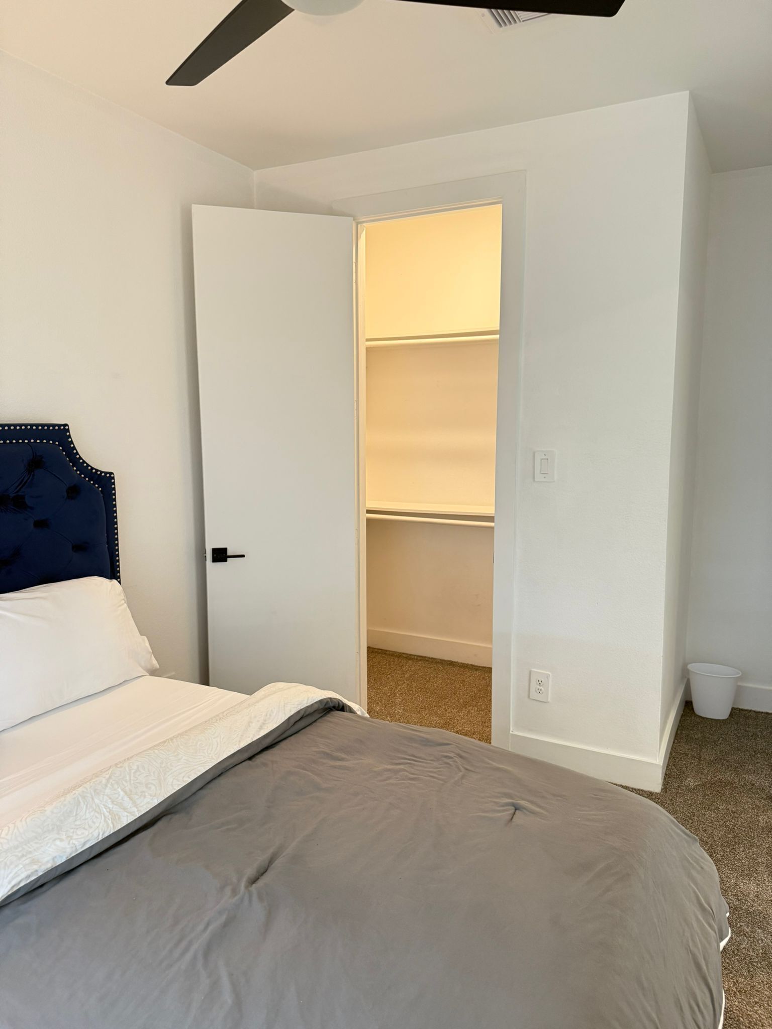 Une chambre à coucher avec un lit, une armoire et un ventilateur de plafond.