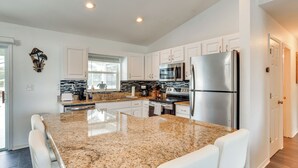 A modern kitchen with white cabinets, granite countertops, stainless steel appliances, and a large island with seating. - 5 Mi to Highlands Hammock: Home w/ Fenced-In Yard (Sebring)