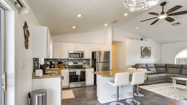 A modern kitchen with white cabinets, stainless steel appliances, and a central island with bar stools. - 5 Mi to Highlands Hammock: Home w/ Fenced-In Yard (Sebring)