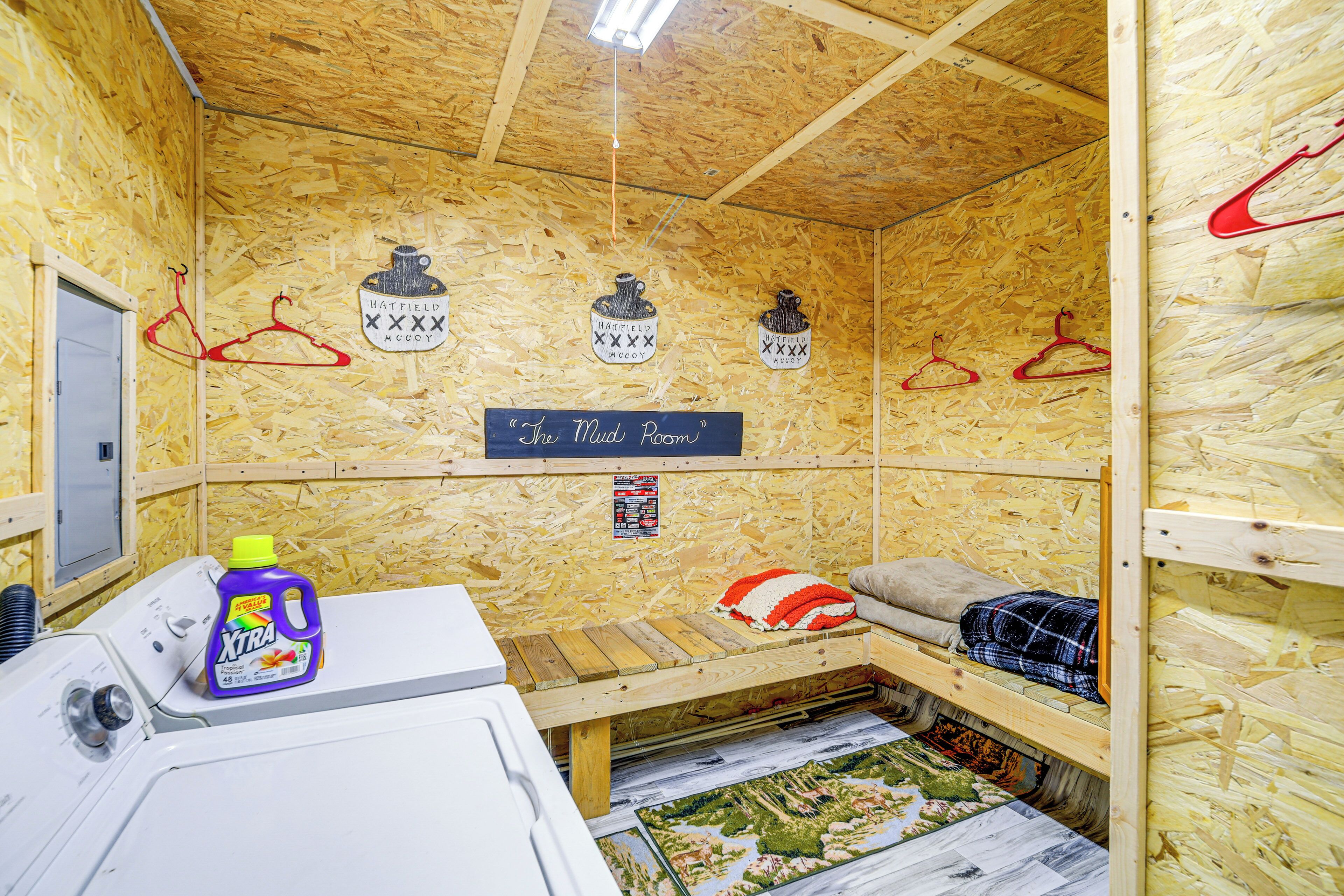 A small, wooden room with bunk beds, a washing machine, and a sign reading "The Mud Room".