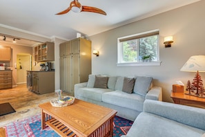 Een moderne woonkamer met een grijze bank, een houten salontafel en een plafondventilator.