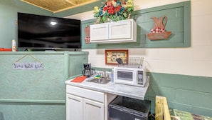 Een keuken met een flatscreen televisie, een magnetron, een spoelbak en een bordje met de tekst 'Home Sweet Home'.