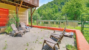 Een terras met Adirondack-stoelen, een kleine tafel en een houten terras dat uitkijkt over een bebost gebied.
