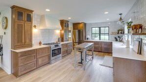 A modern kitchen with wooden cabinets, stainless steel appliances, and a central island. - Cabin on 28 Acres: Hike & Fish in Flathead Valley! (Marion)