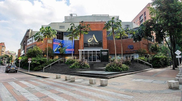 A modern building with a prominent 'A' logo, featuring a central entrance with steps, surrounded by palm trees and a landscaped area.
