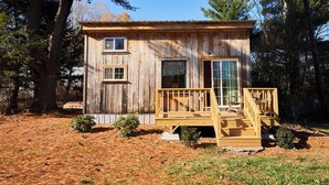 A small wooden cabin with a front porch, two windows, and a door.