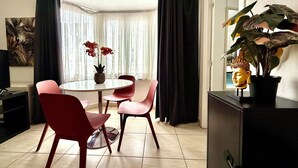 Een moderne eethoek met een ronde tafel, rode stoelen en een potplant.