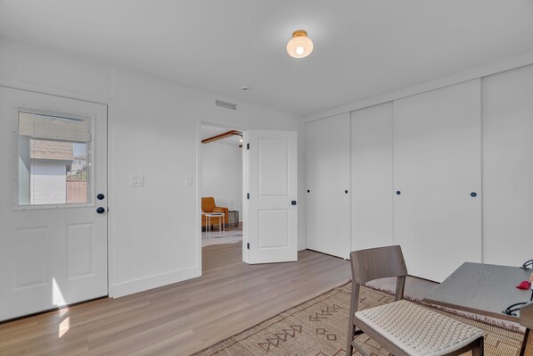 Une pièce avec un plancher en bois, des murs blancs, une table à manger avec des chaises et un tapis à motifs.