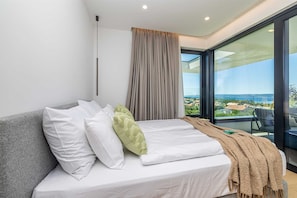 A modern bedroom with a bed, a view of the outdoors, and a large window. - Luxury villa 45° with infinity pool (Punat)
