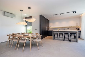 Una cocina moderna con una isla central, taburetes de bar e iluminación colgante.