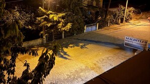 A nighttime view of a paved area with a sign for 'MALDIVLER CAFE & PANNYON' and surrounding trees. - maldivler pansiyon (Yesilova)