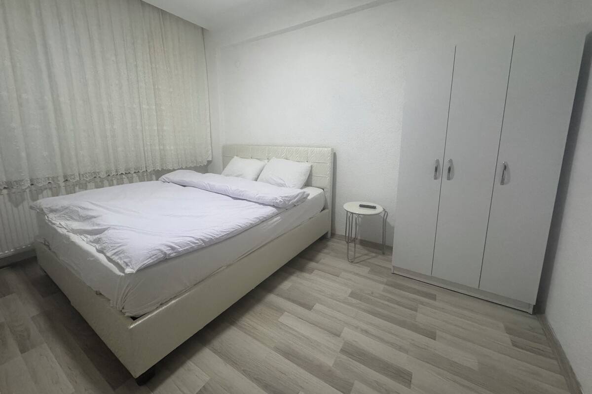 A bedroom with a bed, a small table, and a wardrobe.
