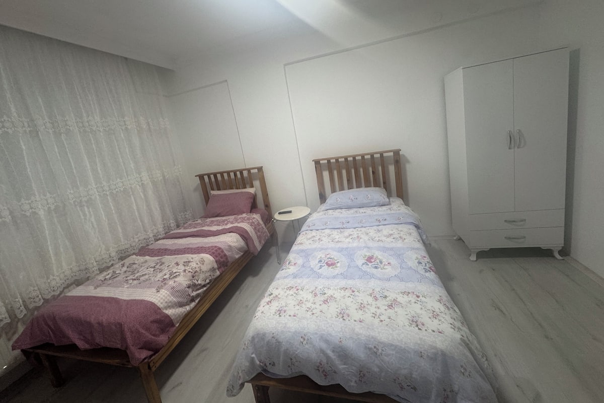A bedroom with two single beds, a wardrobe, and a small bedside table.