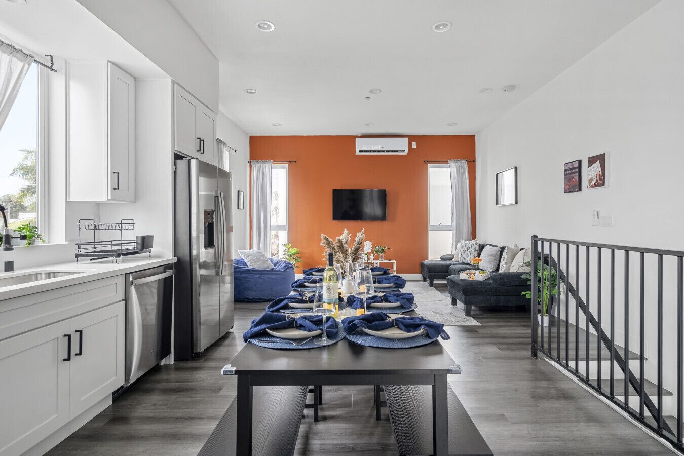 A modern kitchen with white cabinets, a stainless steel refrigerator, and a dining area with a table set for four.