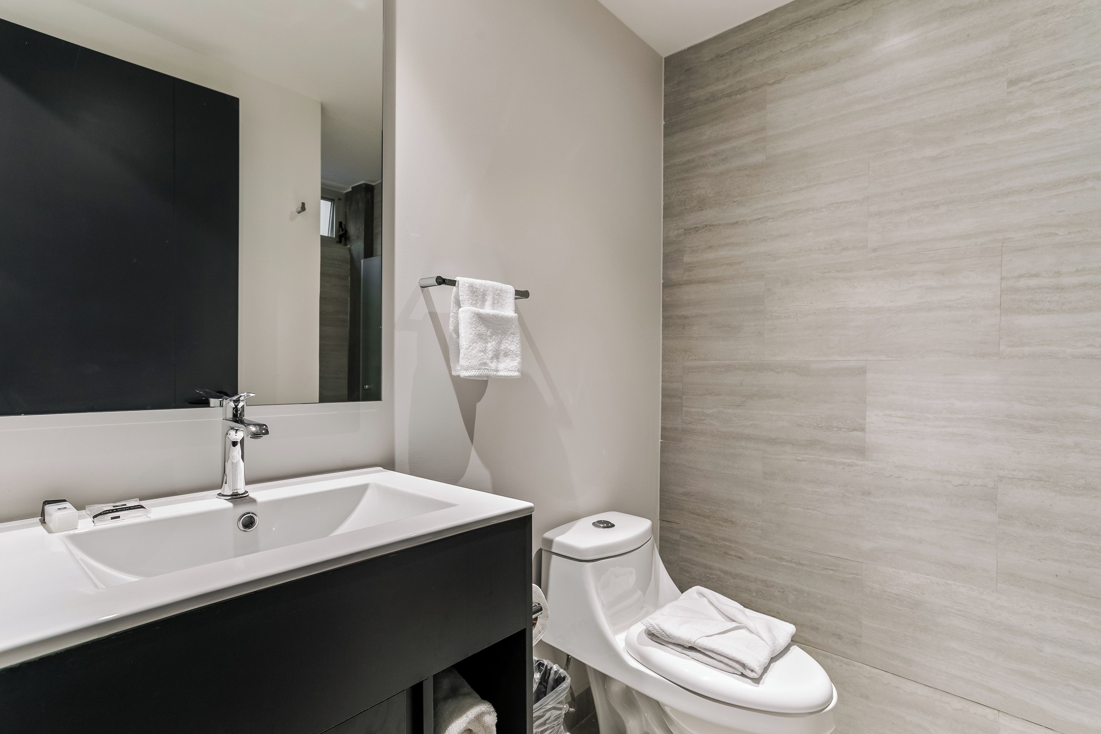 Et moderne badeværelse med en hvid vask, et spejl og et toilet.