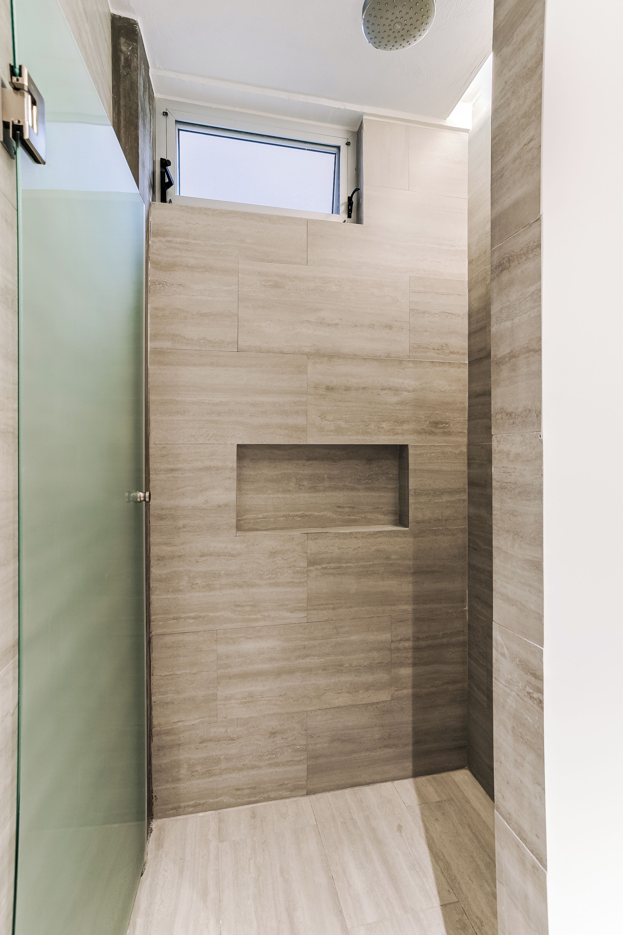 A shower area with a recessed window and a built-in shelf.