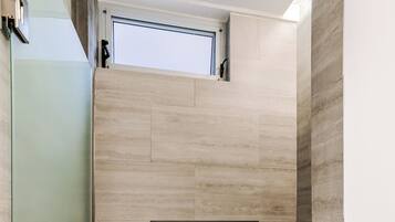 A shower area with a recessed window and a built-in shelf.