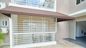 A building with a covered outdoor seating area, a fire extinguisher, and a security gate. - Charming 3-bedroom apartment with Wi-Fi, AC in welcoming Santo Domingo Este. (Santo Domingo Este)