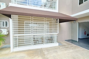 A building with a covered outdoor seating area, a fire extinguisher, and a security gate. - Charming 3-bedroom apartment with Wi-Fi, AC in welcoming Santo Domingo Este. (Santo Domingo Este)