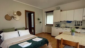 Una habitación compacta con cama, una pequeña mesa de comedor y una kitchenette.