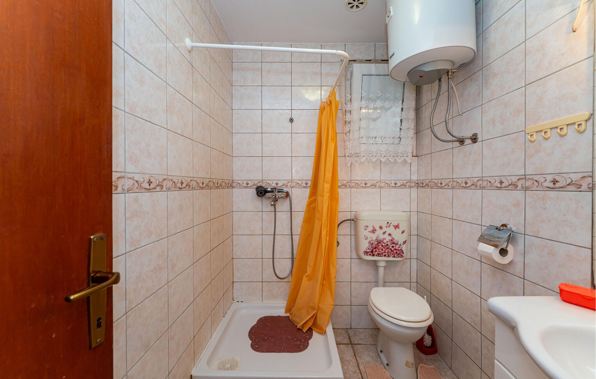 A small bathroom with a shower, toilet, and sink.