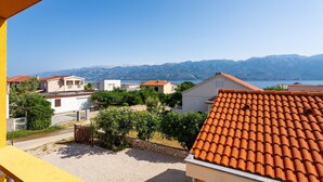 A coastal residential area with terracotta-tiled roofs, a clear view of the sea, and mountains in the background. - 1 bedroom cozy apartment in Razanac (Razanac)