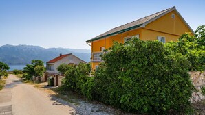 A coastal road with a yellow building and a smaller white building. - 1 bedroom cozy apartment in Razanac (Razanac)