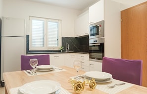 A modern kitchen with white cabinets, a black countertop, and stainless steel appliances including a microwave and oven.