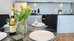A dining table set with plates, glasses, and a bottle of wine, with a vase of tulips in the background.