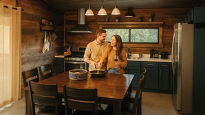 A wooden cabin interior with a dining table, chairs, a stove, and a refrigerator. - Luxury S Austin Home + Casita (Austin)